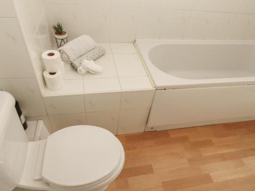 a white bathroom with a toilet and a tub at Curwen Apartment in Workington