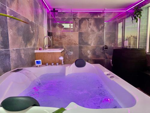 a bathroom with a large tub with purple lighting at Glücklich am Meer Apartment Deluxe mit Wellnesszugang in Egmond aan Zee