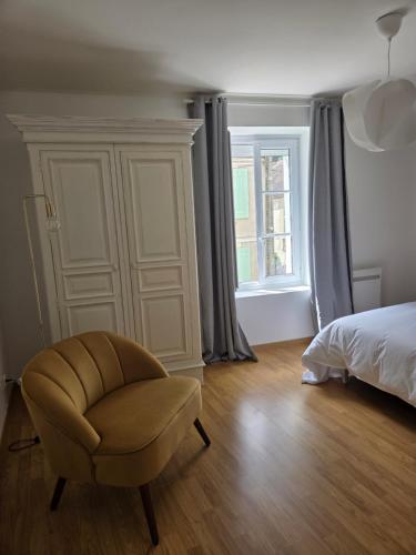 a bedroom with a chair and a bed and a window at La belle échappée in Recloses