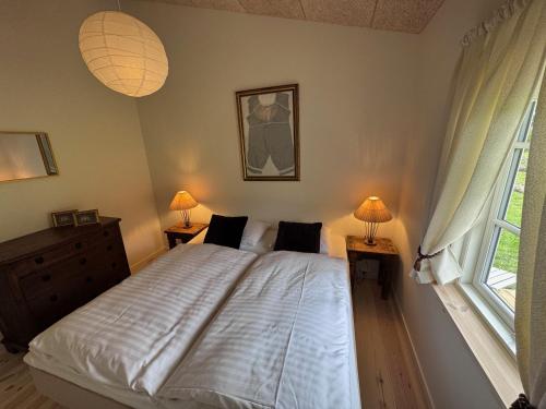 a bedroom with a bed with two lamps and a window at Pension Lærkelill in Skovlund