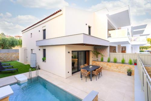 a white house with a swimming pool in front of it at Villa El Mar in Gerakini