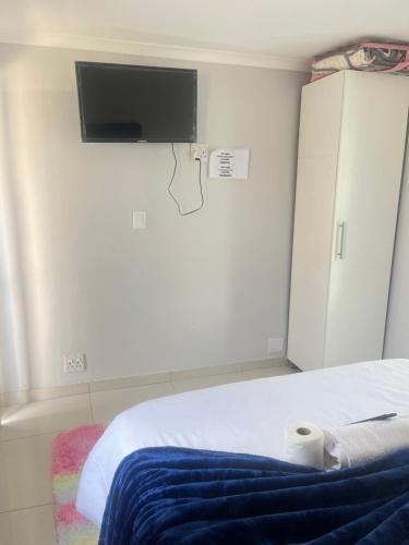 a bedroom with a bed with a tv on the wall at The Perfect Place in Parow