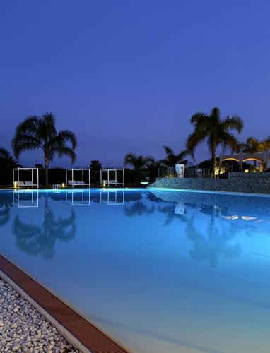 a large swimming pool with blue water at night at Wellness Spa Hotel Principe Fitalia in Siracusa
