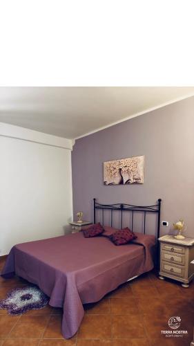 a bedroom with a bed with a purple bedspread at Agriturismo Terra Nostra in San Mauro Cilento