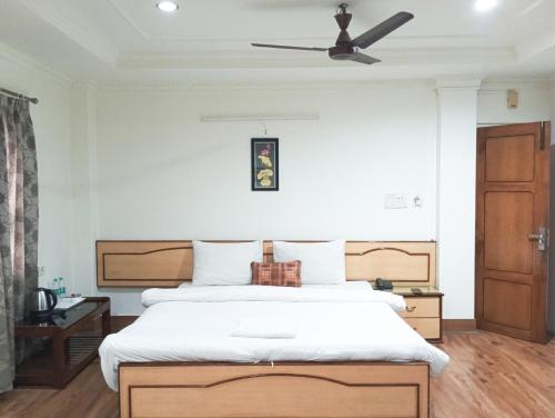 a bedroom with a bed and a ceiling fan at Hotel Vinayak in Siliguri