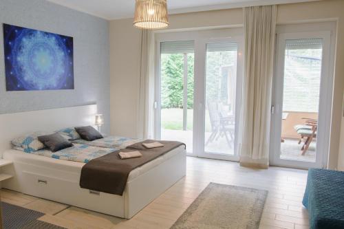 a bedroom with a bed in a room with sliding glass doors at Szíriusz Apartmanház in Gyula