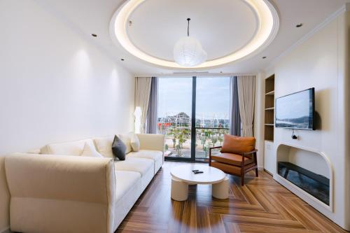a living room with a white couch and a large window at HN Apartment and Hotel in Tài Xá