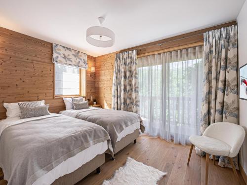 a bedroom with two beds and a window at Chalet moderne et cosy avec jacuzzi, sauna et parking à Méribel - FR-1-565-1 in Les Allues