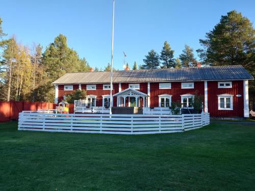 ein rotes Haus mit einem weißen Zaun davor in der Unterkunft Jävregården in Jävre