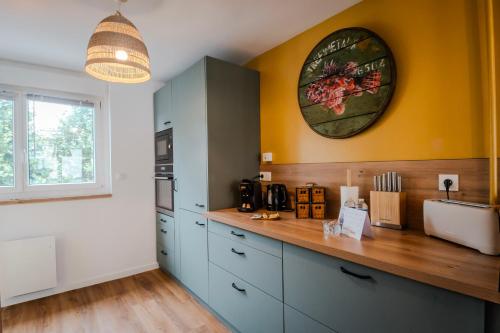 une cuisine avec des placards bleus et une horloge murale dans l'établissement Evasion Urbaine - Balnéothérapie - By Primo conclergerie, à Caen