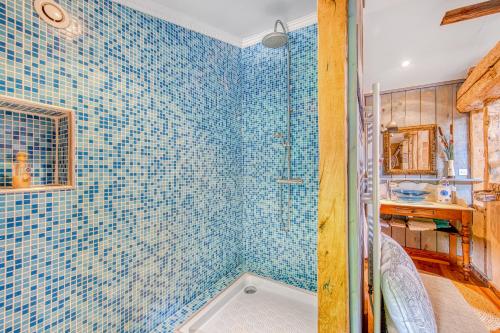 a bathroom with blue tiled walls and a shower at Chambre Mansarde - L'orée De Lansot in Noaillan