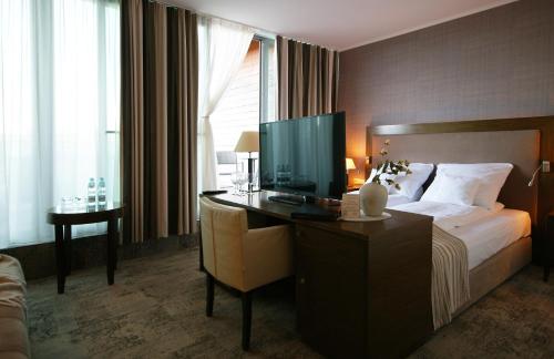 a hotel room with a bed and a desk with a television at Apartamenty IRS Havet in Dźwirzyno