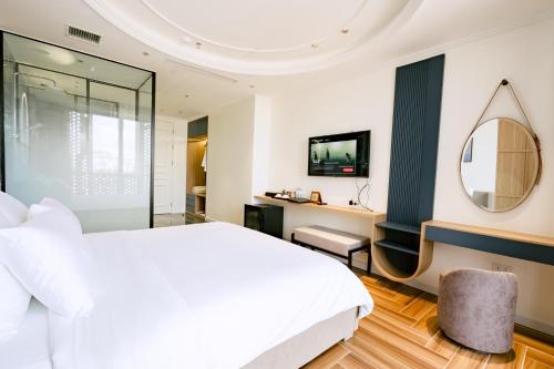 a bedroom with a large white bed and a mirror at HN Apartment and Hotel in Tài Xá