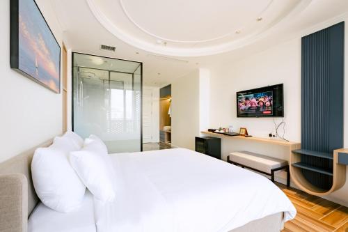 a bedroom with a white bed and a tv at HN Apartment and Hotel in Tài Xá