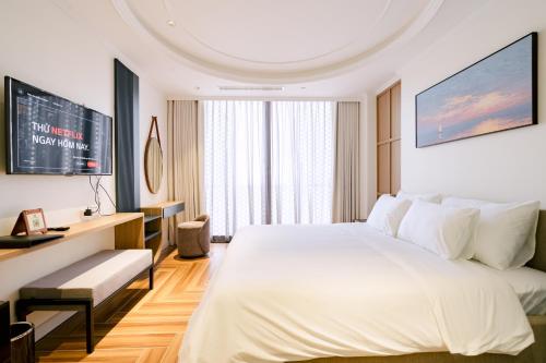 a bedroom with a large white bed and a tv at HN Apartment and Hotel in Tài Xá