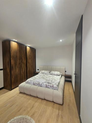 a bedroom with a white bed and wooden cabinets at 3BiS Apartment in Fushë-Krujë