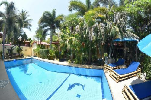 a swimming pool with two chairs and palm trees at Sanuk bungalows in Rawai Beach