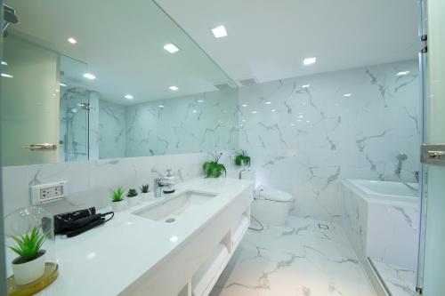 a white bathroom with a sink and a mirror at Civic Park in Bangkok