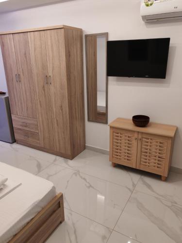 a living room with a tv and wooden cabinets at Premium Studio Family II in Paralia Katerinis