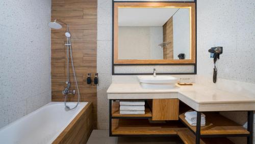 a bathroom with a sink and a tub and a mirror at Grand Sunshine Resort & Convention in Bandung