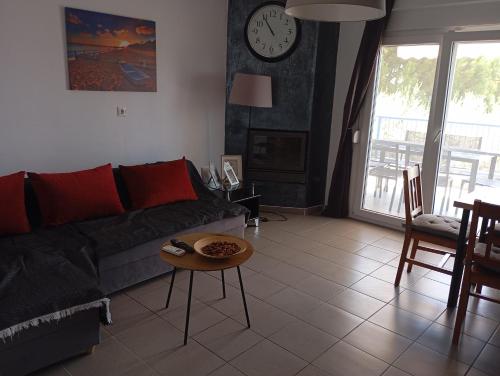 a living room with a couch and a table and a clock at Dream house by the sea in Mola Kalyva