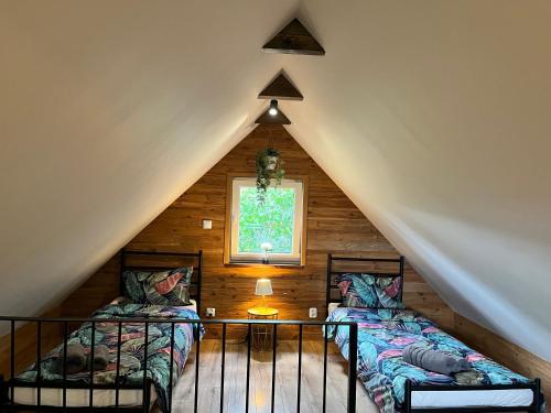 a attic room with two beds and a window at Mazurska Łąka in Piecki