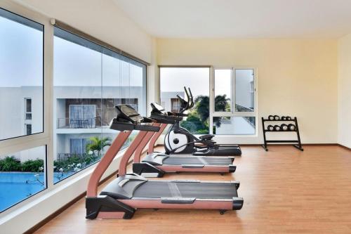a gym with a row of exercise bikes in a room with windows at Four Points by Sheraton Mahabalipuram Resort & Convention Center in Mahabalipuram
