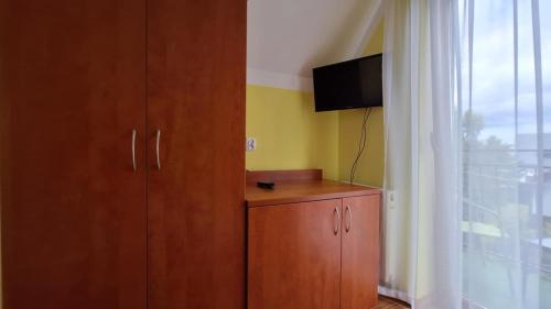 a room with a cabinet and a tv and a window at Rafa in Trzęsacz