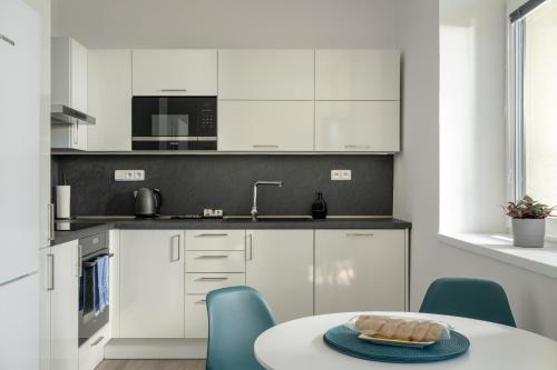 a kitchen with white cabinets and a table and chairs at Apartmány v Rezidenci Podhradí in Štramberk