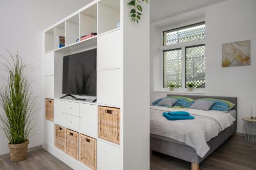 a white bedroom with a bed and a tv at Apartmány v Rezidenci Podhradí in Štramberk