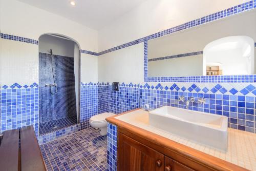 een blauw betegelde badkamer met een wastafel en een toilet bij amazing villa in Es Cubells