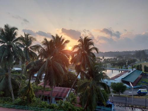 a group of palm trees in front of a sunset at Hotel Amit in Port Blair
