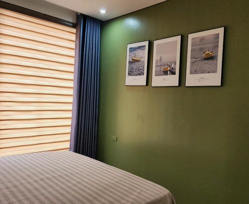a bedroom with four pictures on a green wall at Homestay Hạ Long NewLife in Kon Rung (1)