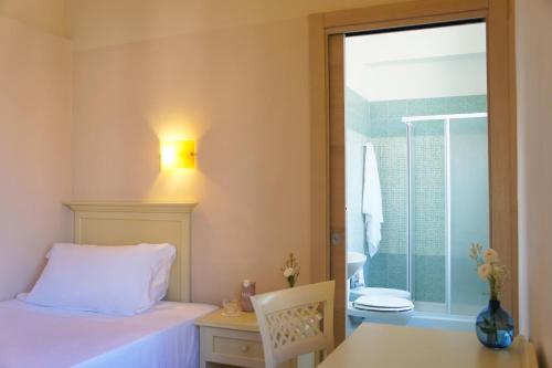 a bedroom with a bed and a bathroom with a window at Hotel le Muse in Siracusa