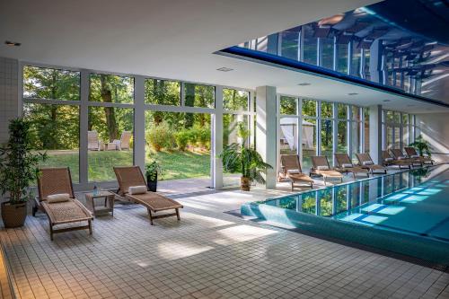 a house with a swimming pool and chairs and windows at Dolce by Wyndham Bad Nauheim in Bad Nauheim