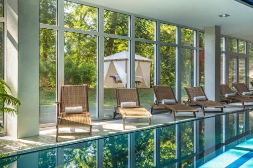 a pool with wicker chairs next to a swimming pool at Dolce by Wyndham Bad Nauheim in Bad Nauheim