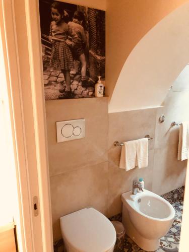 a bathroom with a white toilet and a sink at Tannur Del Carmine in Noto