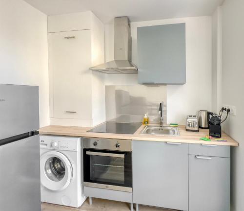 a white kitchen with a sink and a dishwasher at Le City Chic in Compiègne