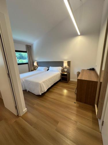 a bedroom with a white bed and a wooden floor at Hotel Solana del Ter in Ripoll