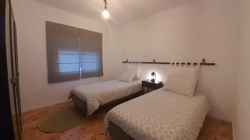 a room with two beds and a window at Adcasinha em Arganil in Adcasal