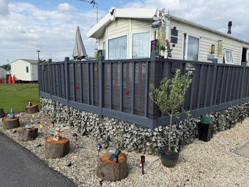 a fence in front of a house with plants at Andreas Fir Trees Retreat at 7 Lakes Country Park in Crowle