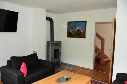 a living room with a black couch and a fireplace at Lärchenheim in Neustift im Stubaital