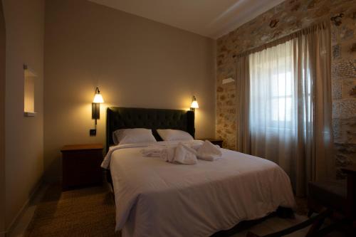 a bedroom with a bed with white sheets and a window at Anemos Suites Mani 