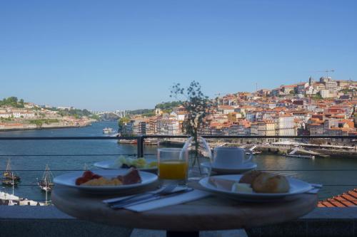 a table with food and drinks and a view of a city at Porto River Soul Hotel in Vila Nova de Gaia