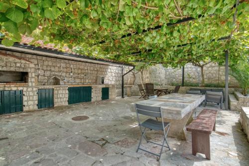 a patio with a table and chairs and vines at Waterfront house with private dock by MN Property in Dobrota