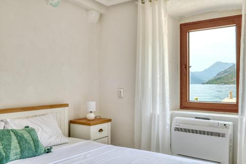 a bedroom with a bed and a window at Waterfront house with private dock by MN Property in Dobrota