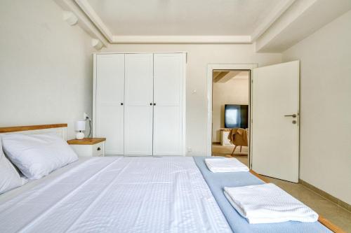 a white bedroom with a large bed with white cabinets at Waterfront house with private dock by MN Property in Dobrota