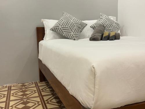 a bed with white sheets and pillows on it at La Luna Inn El Nido in El Nido