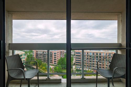 two chairs on a balcony with a view of a city at The Woodlands Waterway Marriott Hotel and Convention Center in The Woodlands