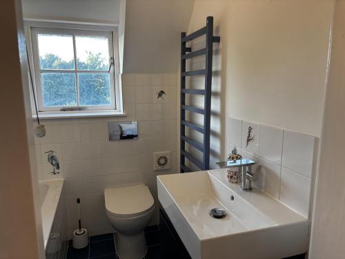 a white bathroom with a toilet and a sink at Bracken Cottage in Weymouth